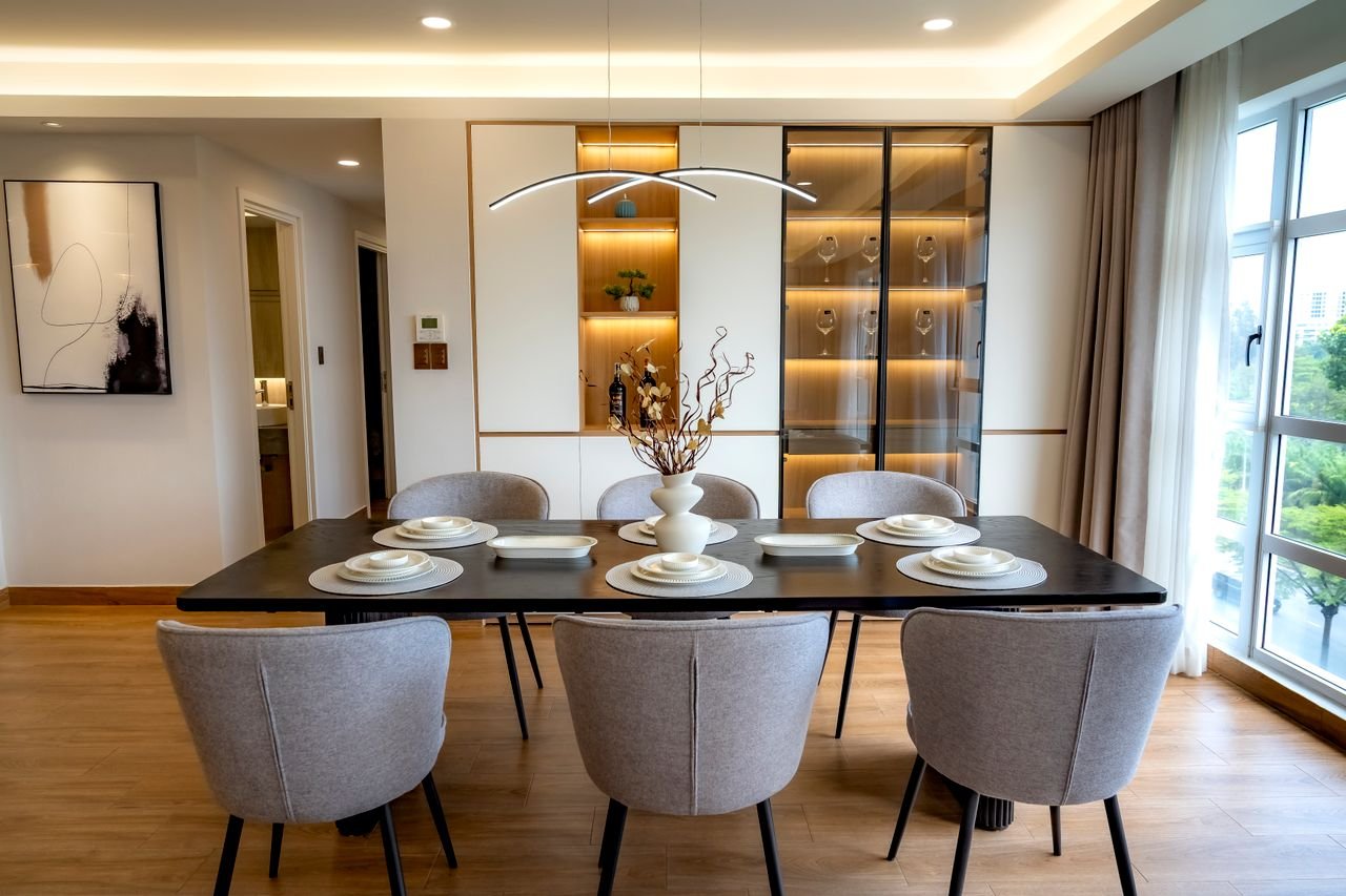 cozy-place Stylish dining room with modern decor, featuring a set table, elegant lighting, and glass cabinet display.